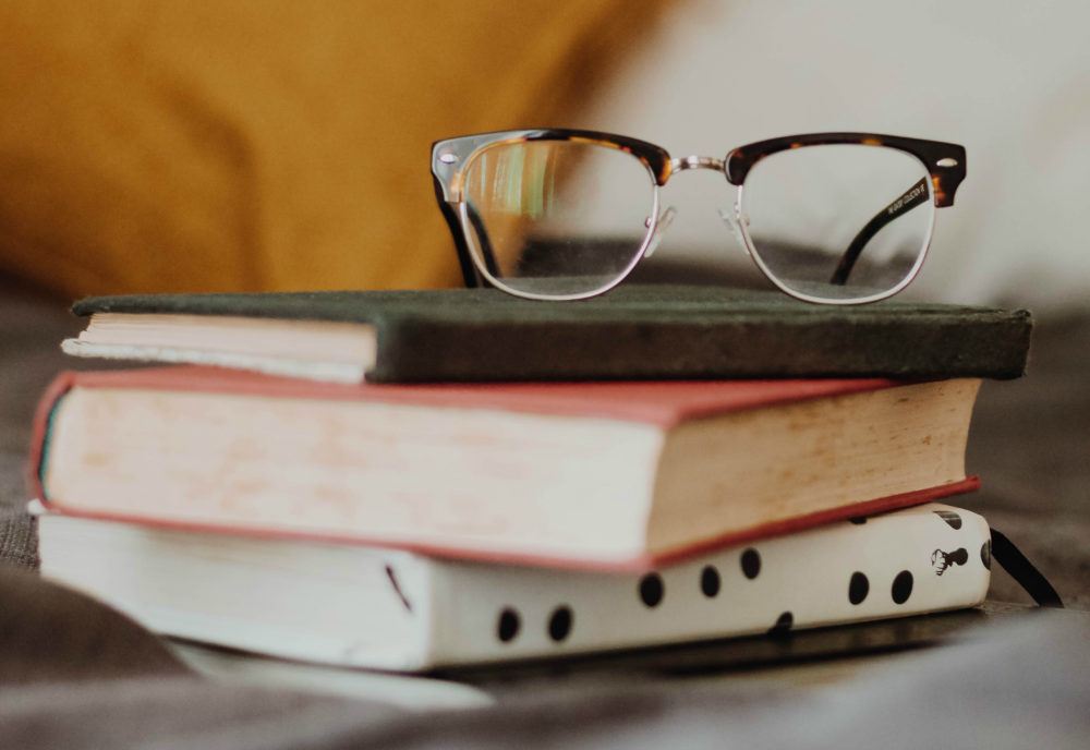 Livros de empreendedorismo empilhados, com um óculos no topo