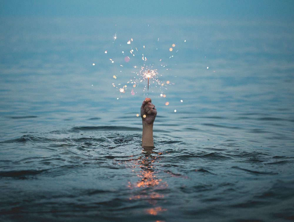 pessoa imersa na água segurando vela de aniversário