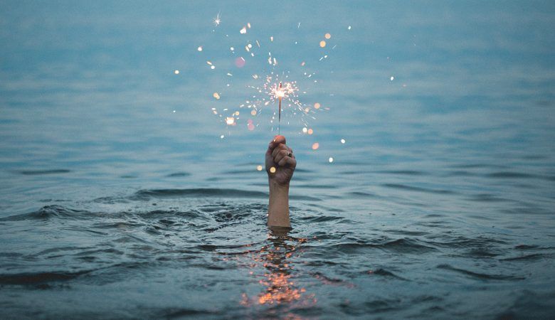 pessoa imersa na água segurando vela de aniversário